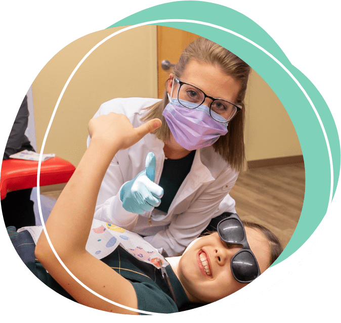 dentist with face mask on helping patient wearing protective eye gear and doing a thumbs up 2